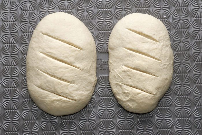 Two loafs slashed by knife on a baking sheet