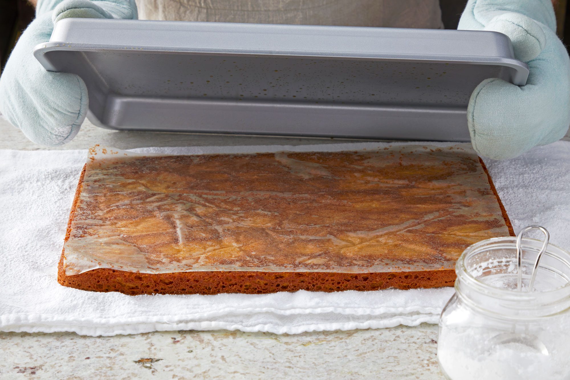 horizontal shot; Turning cake onto a kitchen towel dusted with confectioners’ sugar;