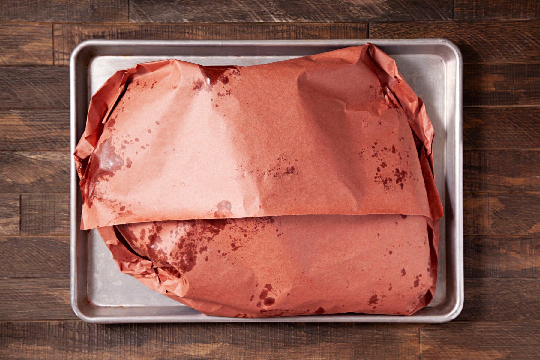 Wrapped beef in unwaxed paper placed in a tray.