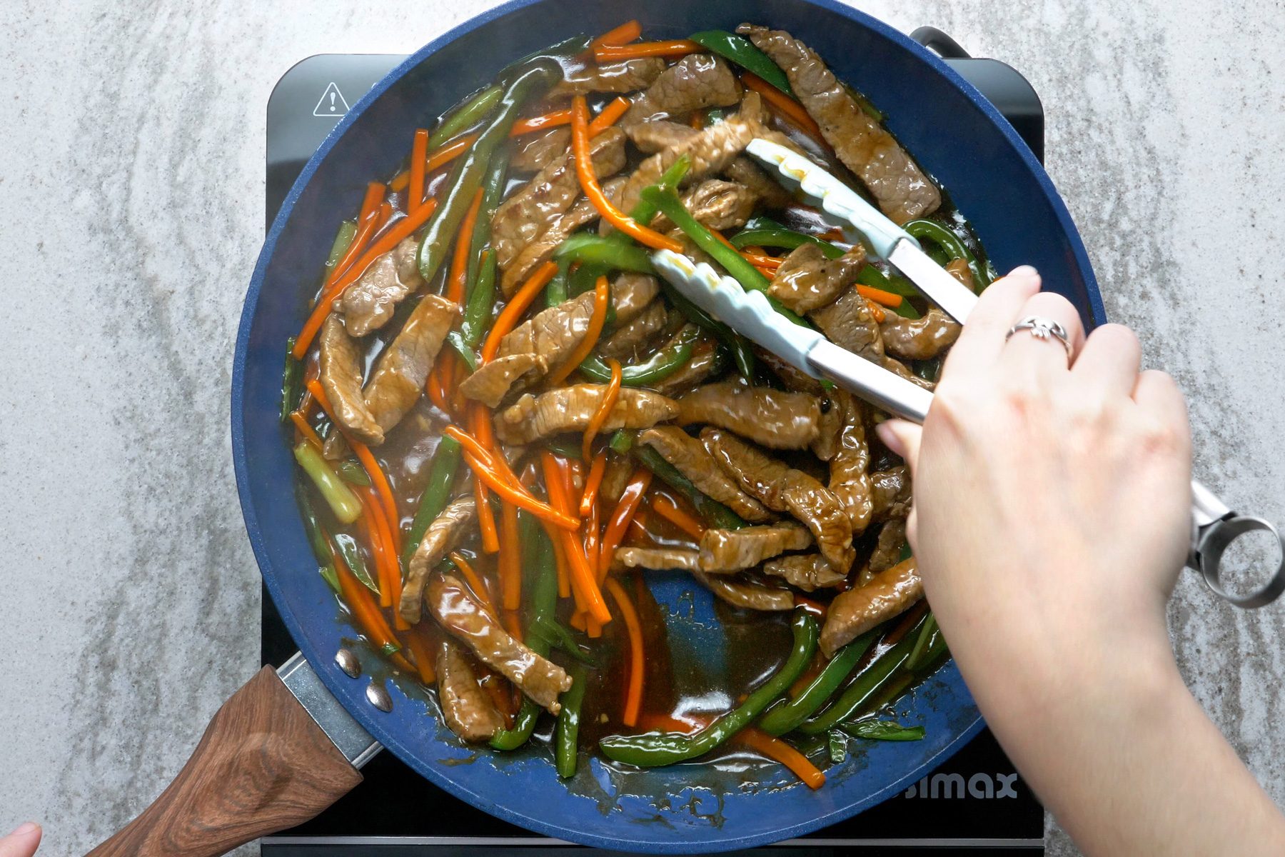 Steak strips with vegetables in a blue skillet