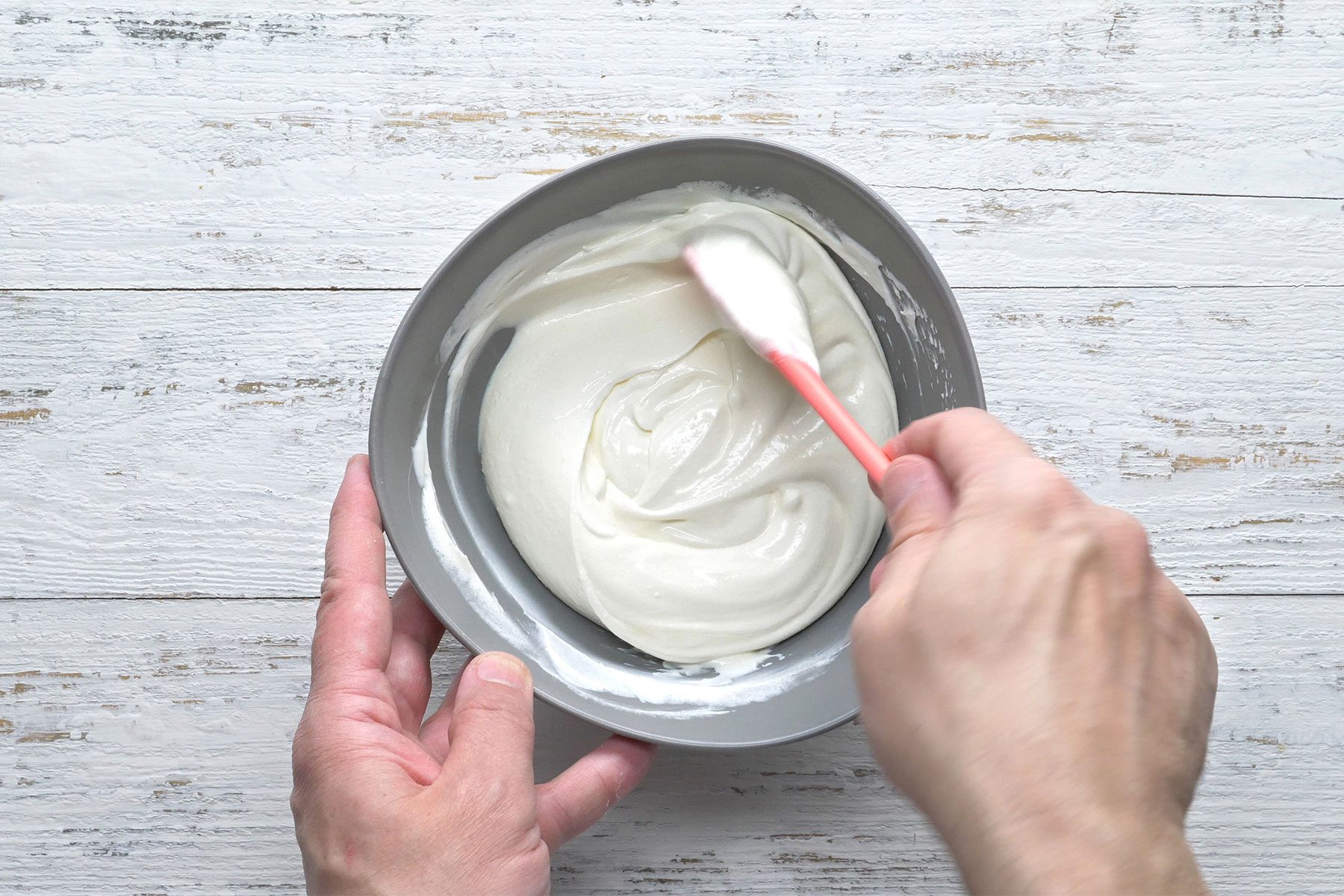 Overhead shot of small bowl; for topping combine sour cream, sugar and vanilla; spoon; wooden background;