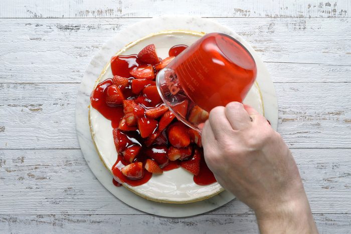 Overhead shot of arrange halved strawberries on top; wooden background;