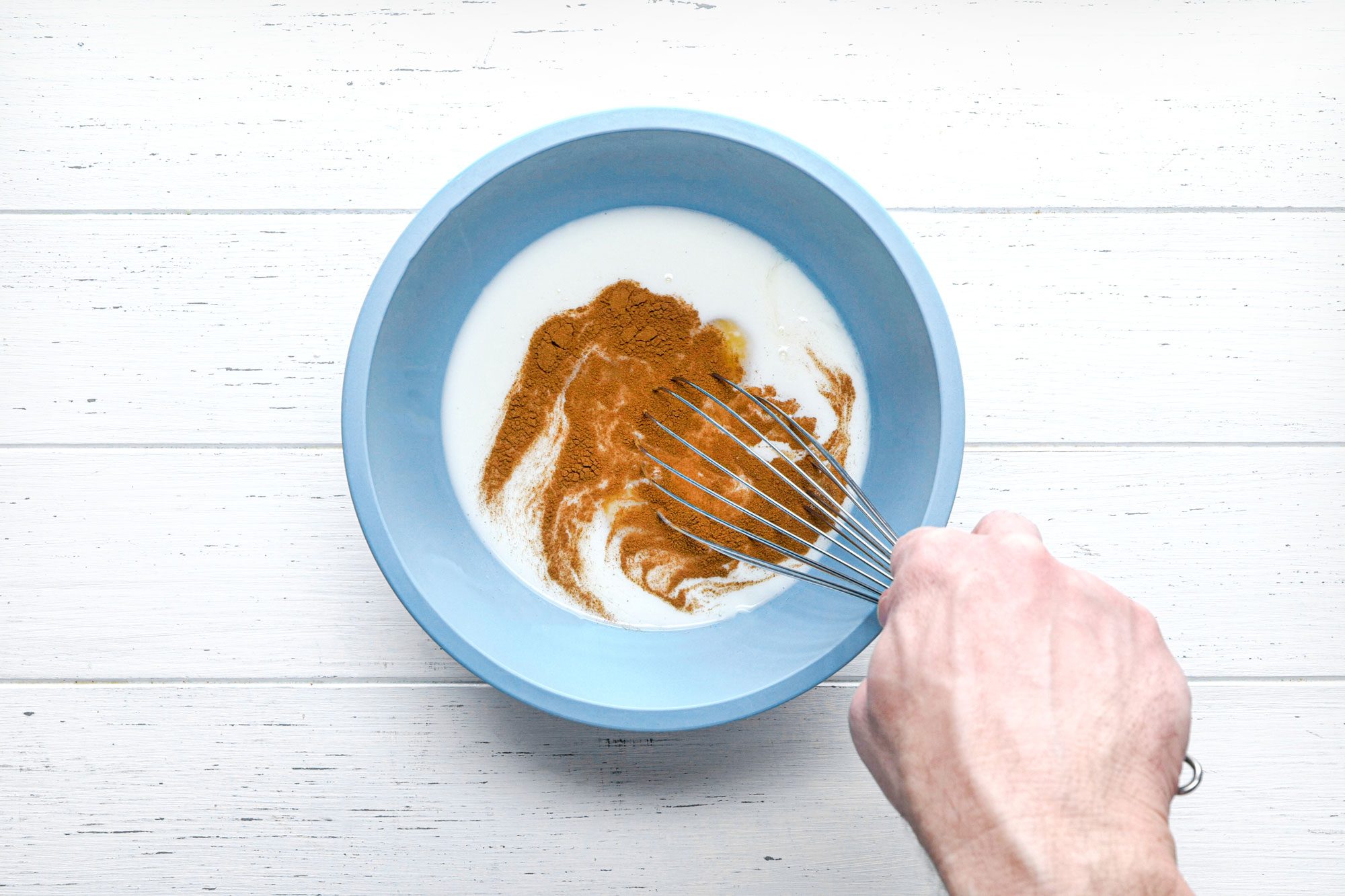 overhead shot of whisked egg mixture with cinnamon in a small bowl