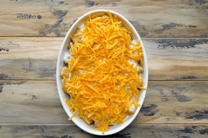 Overhead shot of baking pan; combined soup and milk; pour over potatoes; sprinkle with cheese; and bake; wooden background;