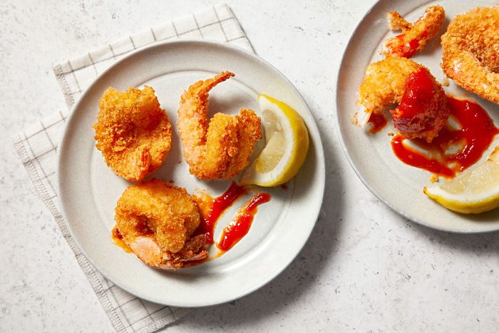 Butterfly Shrimp in a small plate with cocktail sauce and lemon wedges