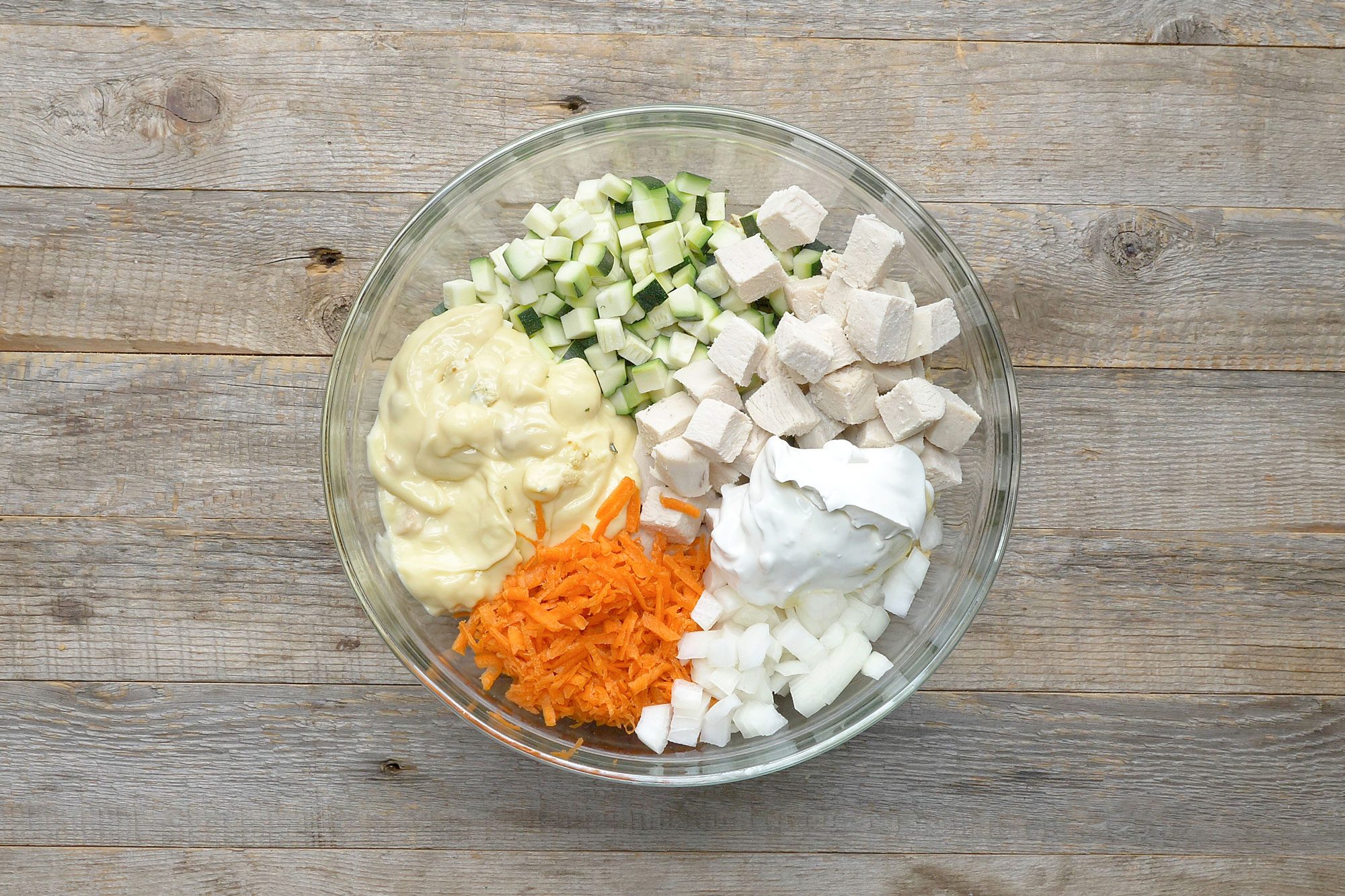 overhead shot of zucchini, cream, chopped veggies and chicken mix in a bowl