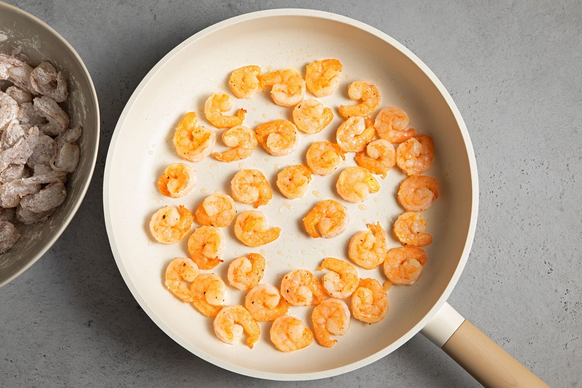 overhead shot of shrimps coated in cornstarch in a large skillet