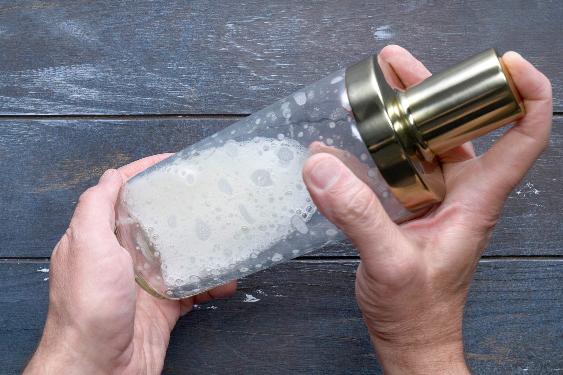 overhead shot; wooden background; shaking the shaker with hands