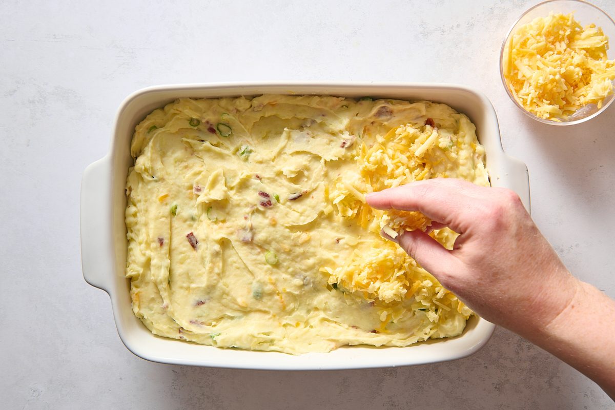 Sprinkling shredded cheese over the potatoes
