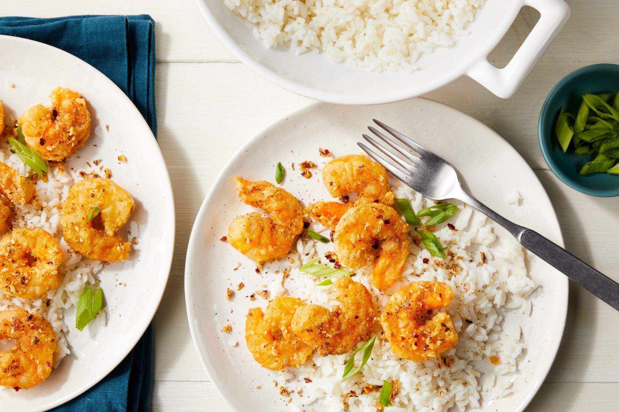 Salt and Ppper Shrimp served on plates with rice and sprinkle green onions over it