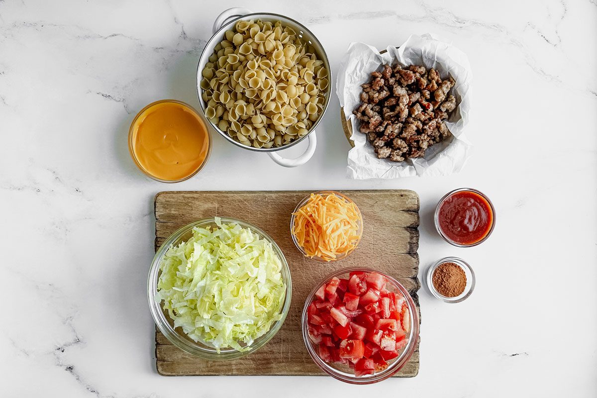 Taste Of Home Taco Mac And Cheese Ingredients Arranged On A Marble Backdrop.