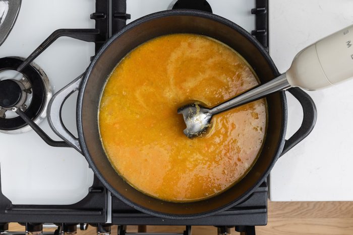 Soup in dutch oven on stove top being blended.