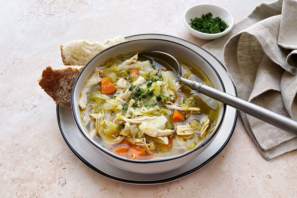 Overhead shot of Taste of Home's Chicken Cabbage Soup on a light stone background