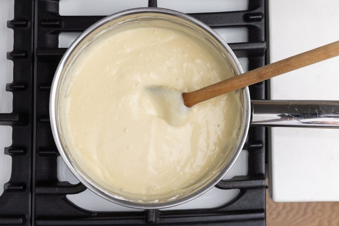 Close up of pot with white sauce being prepared.