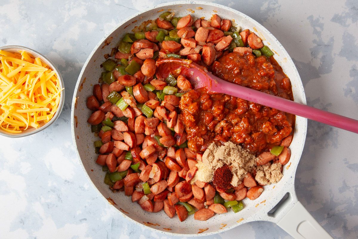 Step 4 of Taste of Home Chili Cheese Dog Casserole is adding in the chili, brown sugar, garlic powder and chili powder into the pan