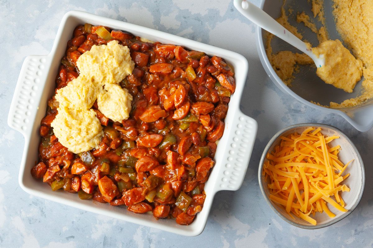 Step 5 of Taste of Home Chili Cheese Dog Casserole is adding the hot dog mixture to the pan, then topping with the rest of the cornbread batter and cheese