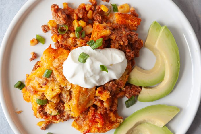 Single serving of Taste of Home Cornbread Taco Bake with sour cream, green onion and avocado