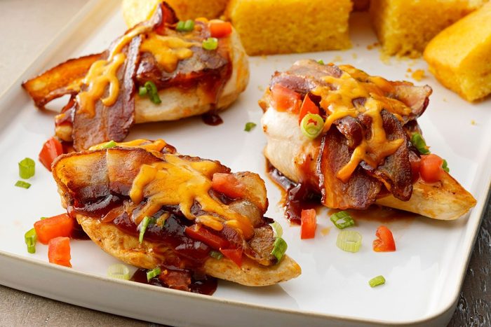 Close up of Monterey Chicken on a tray drizzled with sauce and topped with cheese