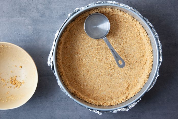 Step 2 of Taste of Home Eggnog Cheesecake is to make the graham cracker crust and press it into the pan before baking