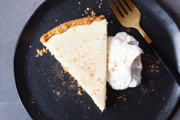 Single serving of Taste of Home Eggnog Cheesecake on a black plate with whipped cream and nutmeg