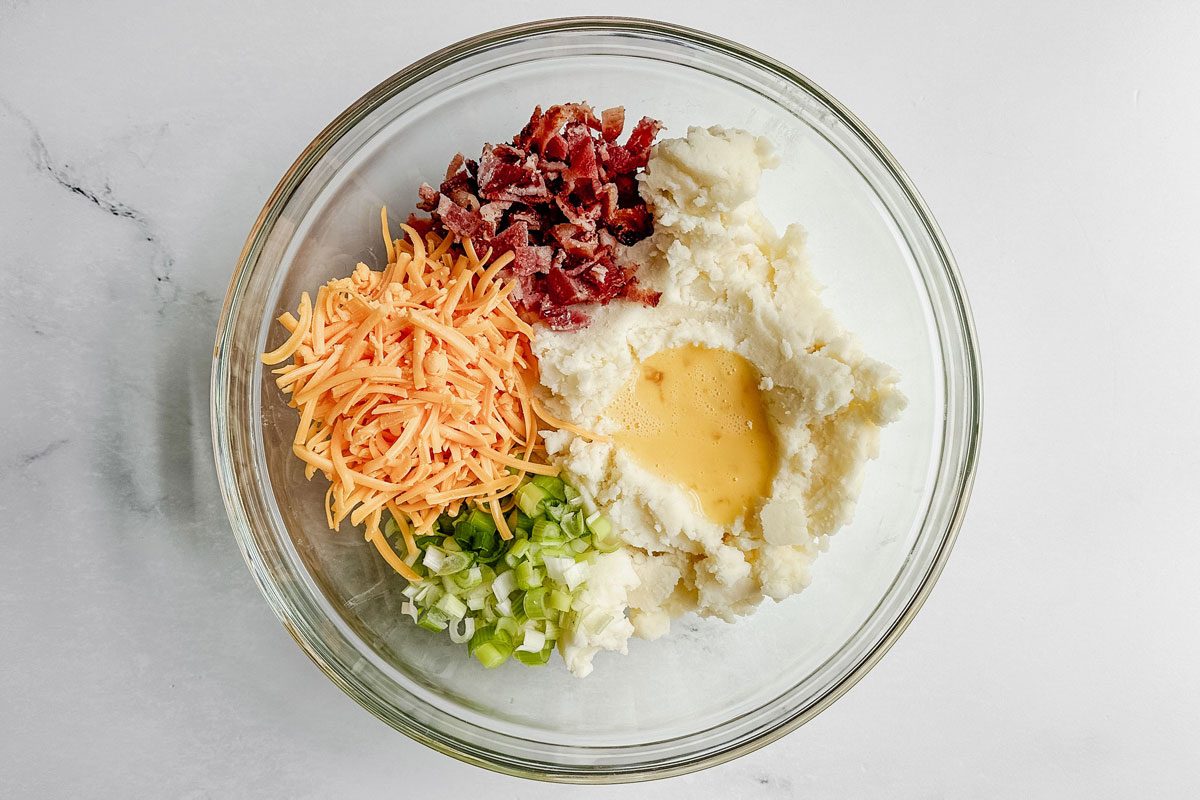 Ingredients for Taste of Home fried mashed potato balls in a glass bowl on a marble surface.