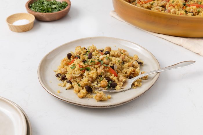 Close up of quinoa chickpea salad on plate with fork and serving dish in the background.