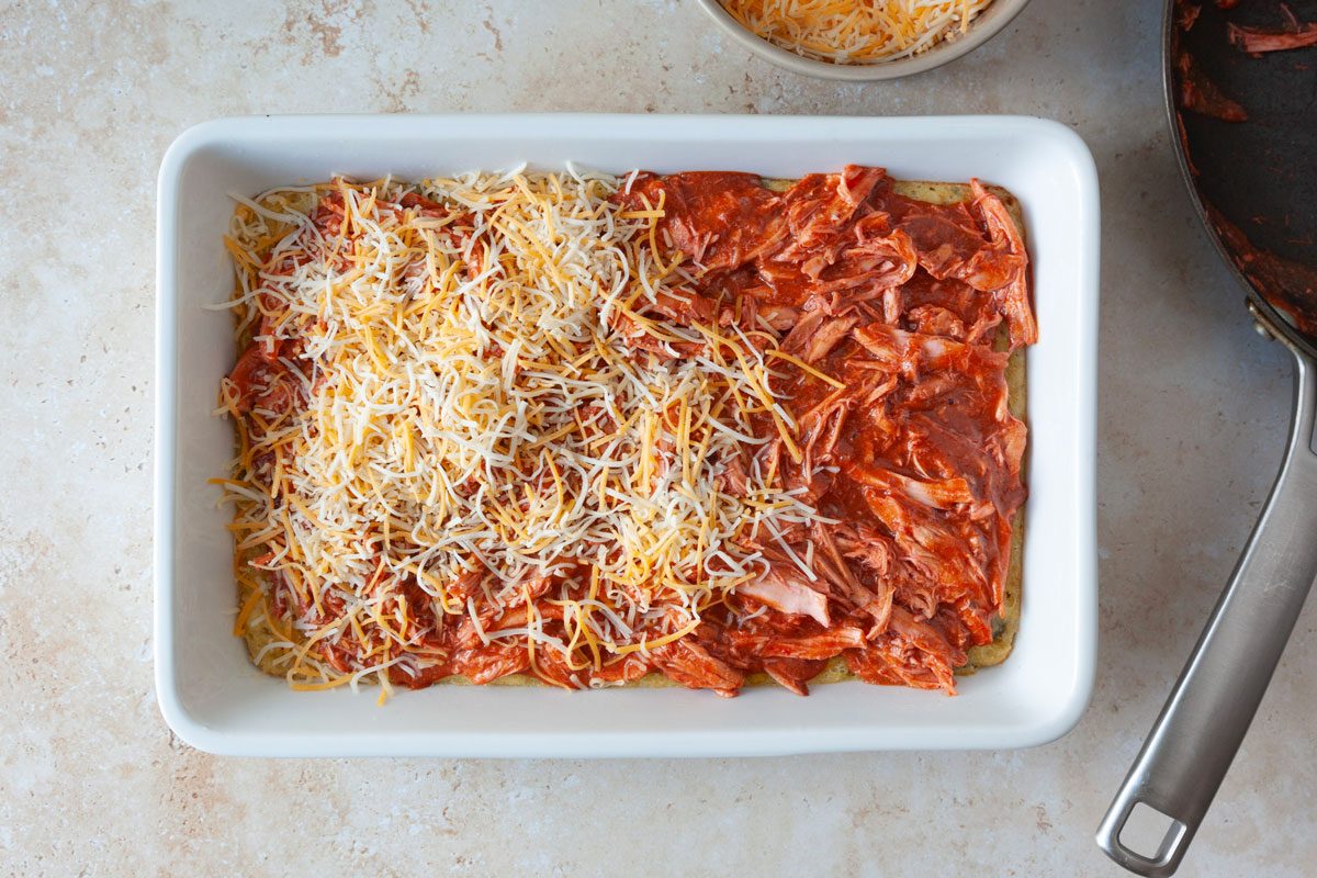 13x9 baking dish with cornbread mixture and topped with shredded chicken, tamale sauce and shredded cheese