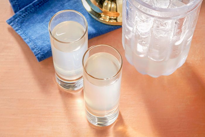 Overhead shot of White Tea Shots; served in two shot glasses; shaker; blue napkin; light orange background;