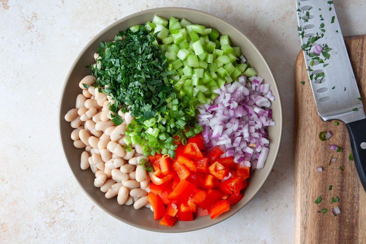 Step 1 of Taste of Home White Bean Salad is to combine all the veggies in a large bowl