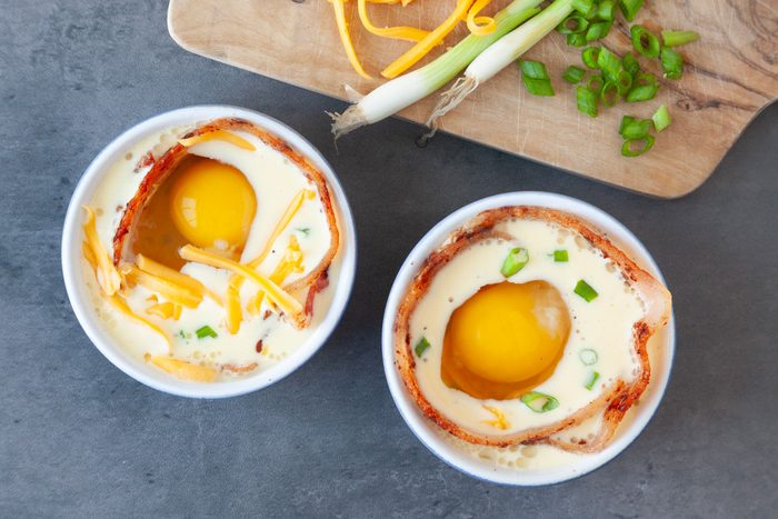 Step 3 of Taste of Home Bacon and Egg Muffins is to line the edges of the ramekins with the bacon strips, then sprinkle half the cheese and onions. Pour in the egg mixture, crack another egg into each one. Top with remaining onions and cheese, bake.