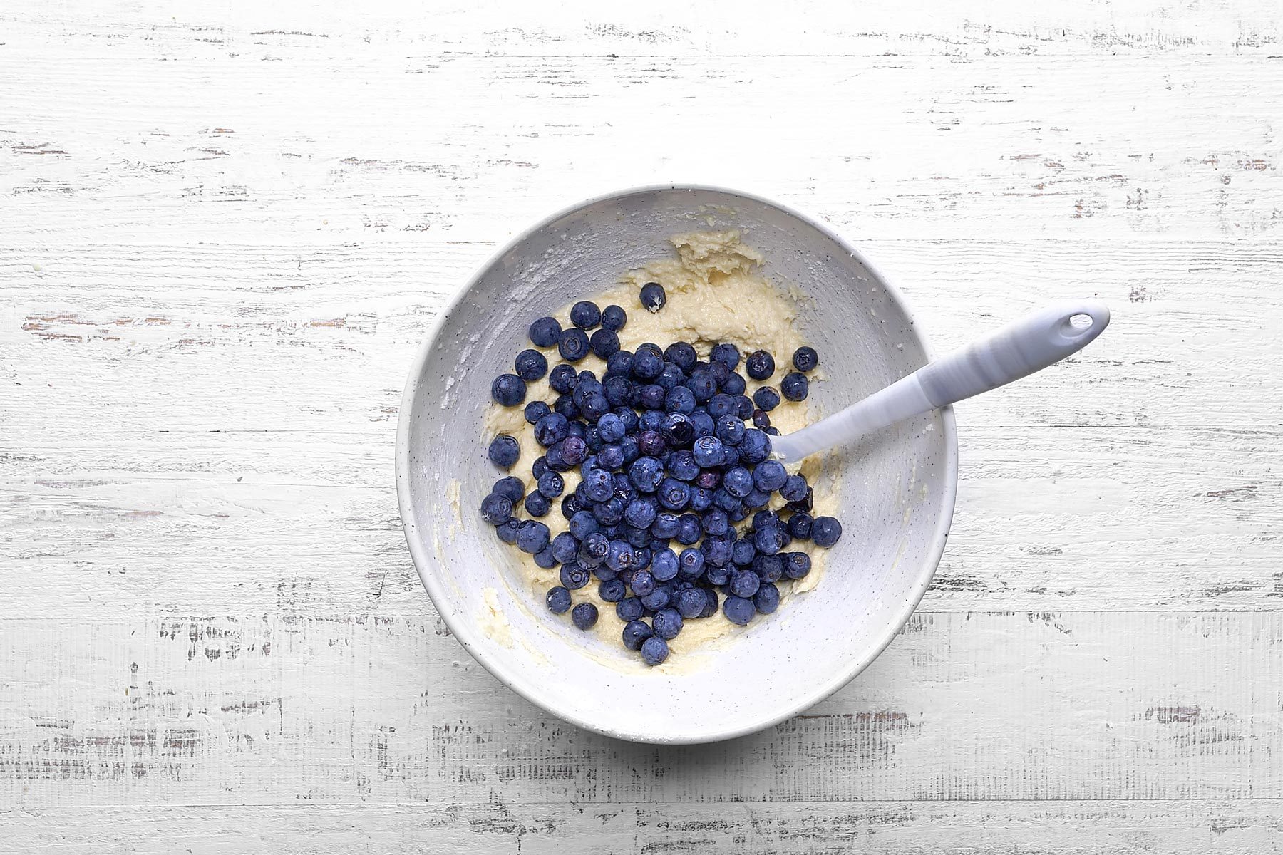Top view shot of folding blueberries in muffin batter