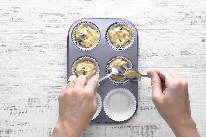 Top view shot of filling muffin baking tray with batter