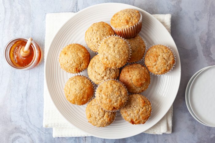 Single servings of Taste of Home Buttermilk Muffins on white plates, glasses of milk, honey