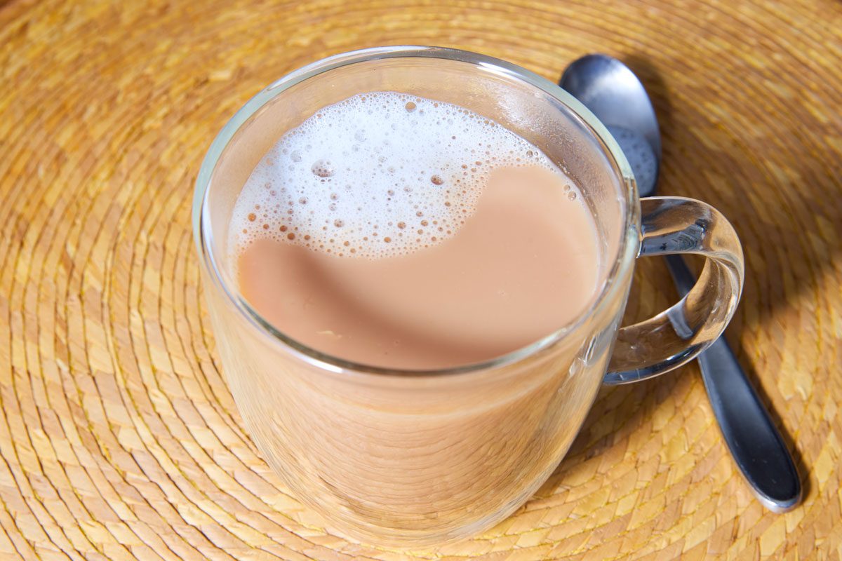 Chai in clear glass mug with stirring spoon along side