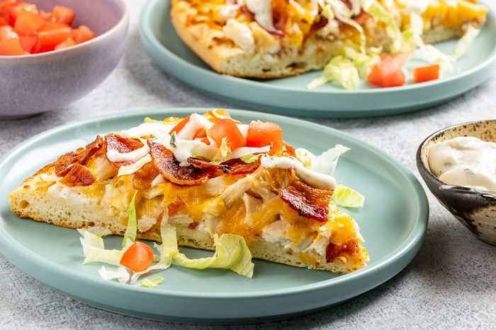 Taste of Home Chicken Bacon Ranch Pizza recipe photo of the pizza sliced and served on plates.