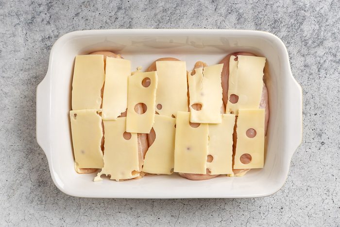 Taste of Home Chicken and Stuffing Casserole recipe photo of chicken topped with sliced swiss cheese in a baking dish.