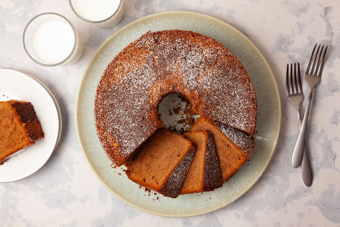 Full yield of Taste of Home Chocolate Pound Cake, a few slices cute, garnished with powdered sugar, cups of milk