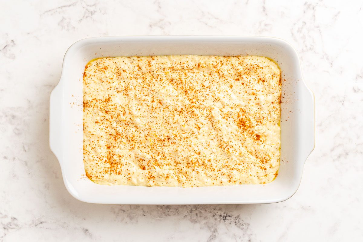 Taste of Home Cornbread Pudding recipe photo of the mixture poured in a baking dish topped with a sprinkle of paprika.