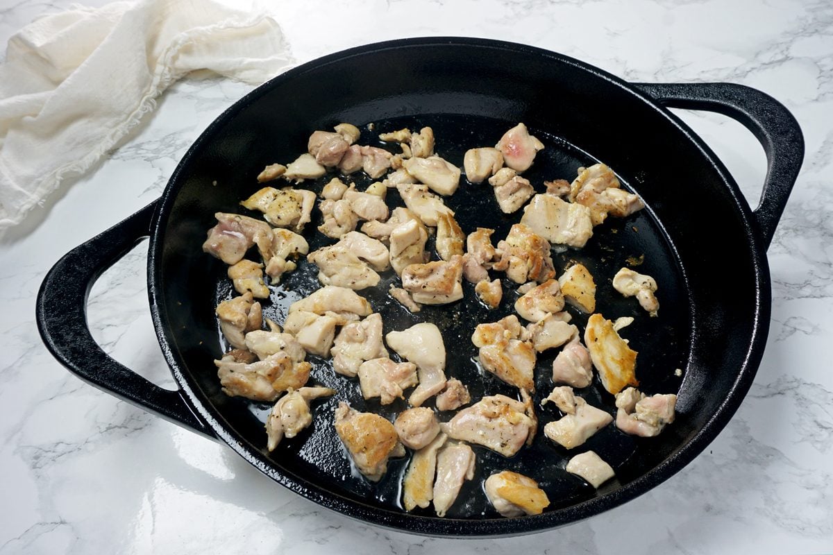 A skillet on a hot plate browning chicken thigh pieces to make Crock-Pot Chicken and Dumplings RMS 201122 for Taste of Home