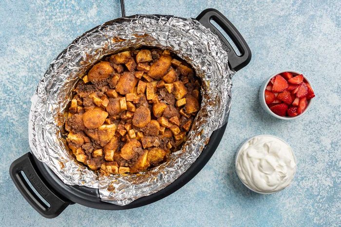 Taste of Home Donut Bread Pudding recipe photo the cooked bread pudding with sides of fresh berries and whipped cream.