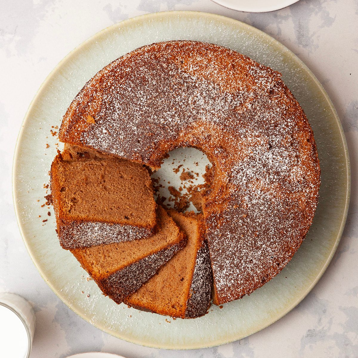 Full yield of Taste of Home Chocolate Pound Cake, a few slices cute, garnished with powdered sugar, cups of milk