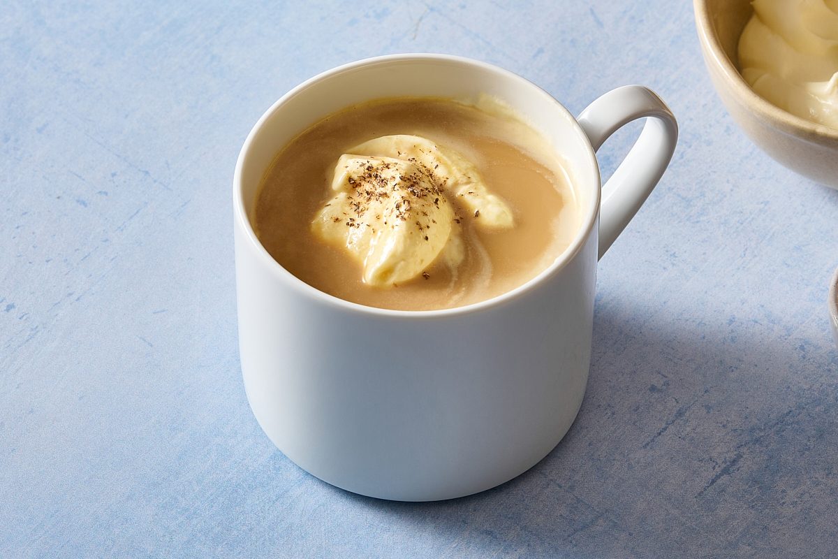 Closeup of a mug of eggnog coffee topped with shipped cream and nutmeg