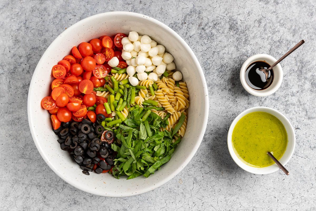 Taste of Home Gluten Free Pasta Salad recipe photo of the assemebled pasta salad in a large bowl with the dressing and balsamic glaze.