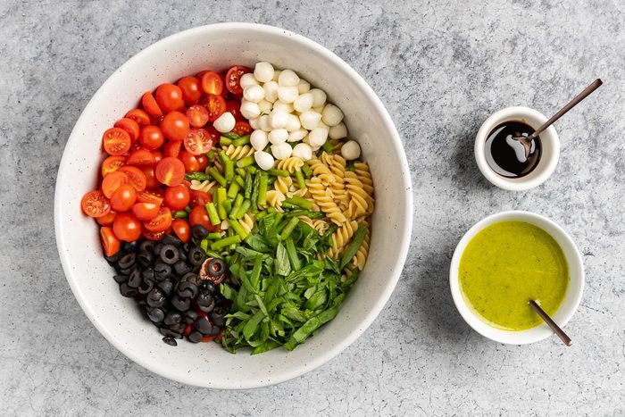 Taste of Home Gluten Free Pasta Salad recipe photo of the assemebled pasta salad in a large bowl with the dressing and balsamic glaze.