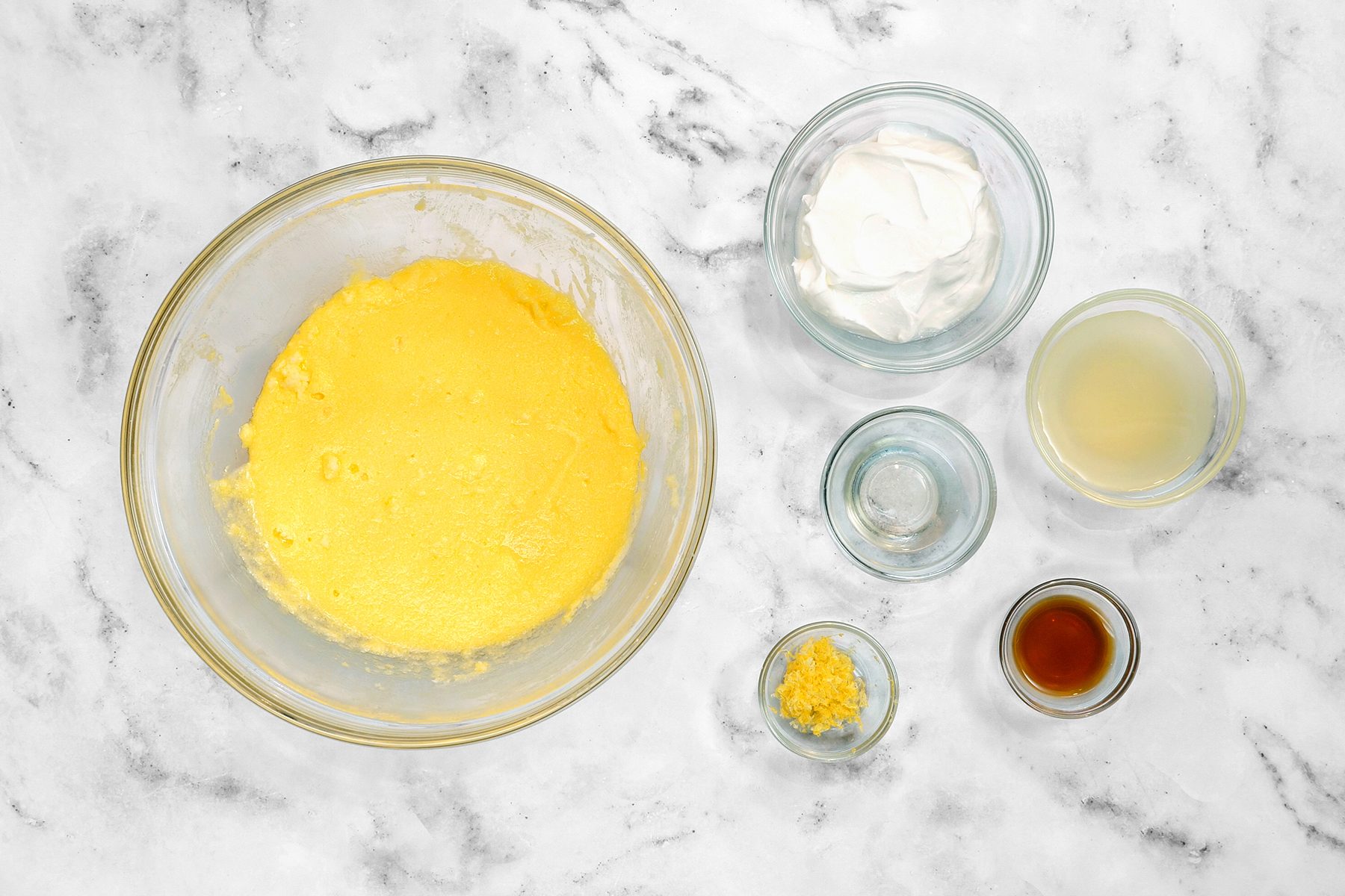 A top view of a marble countertop with ingredients for cake batter.