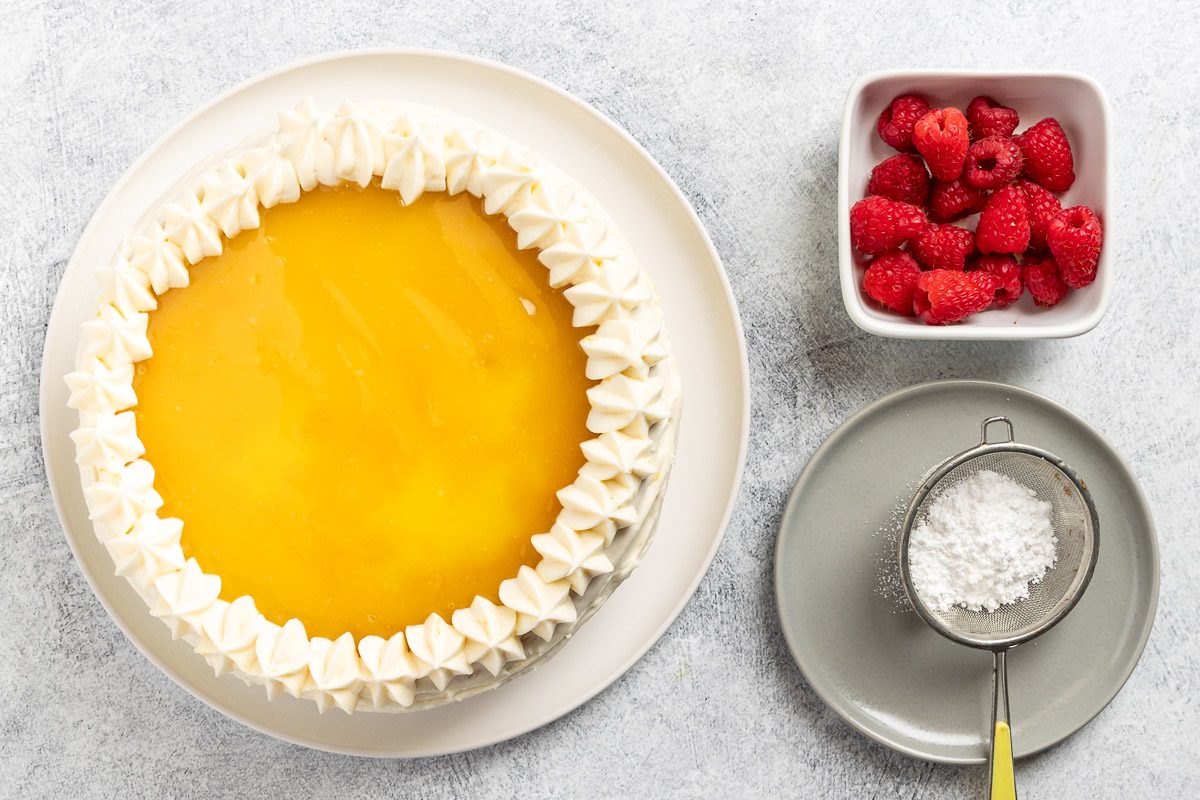 Taste of Home Lemon Raspberry Cake recipe photo of frosting and garnishing the cake.