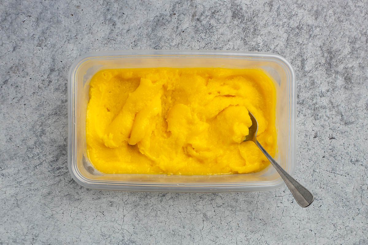Taste of Home mango sorbet recipe photo of the mixture poured into a freezer safe container and turned over with a spoon mid freeze.