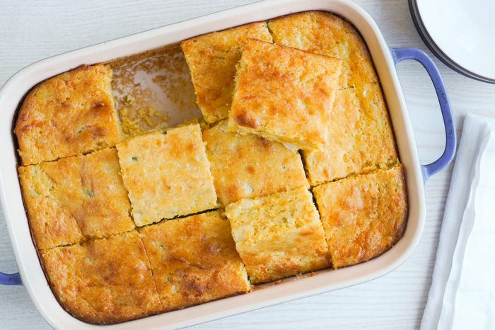 Sliced cheesy cornbread in a casserole dish