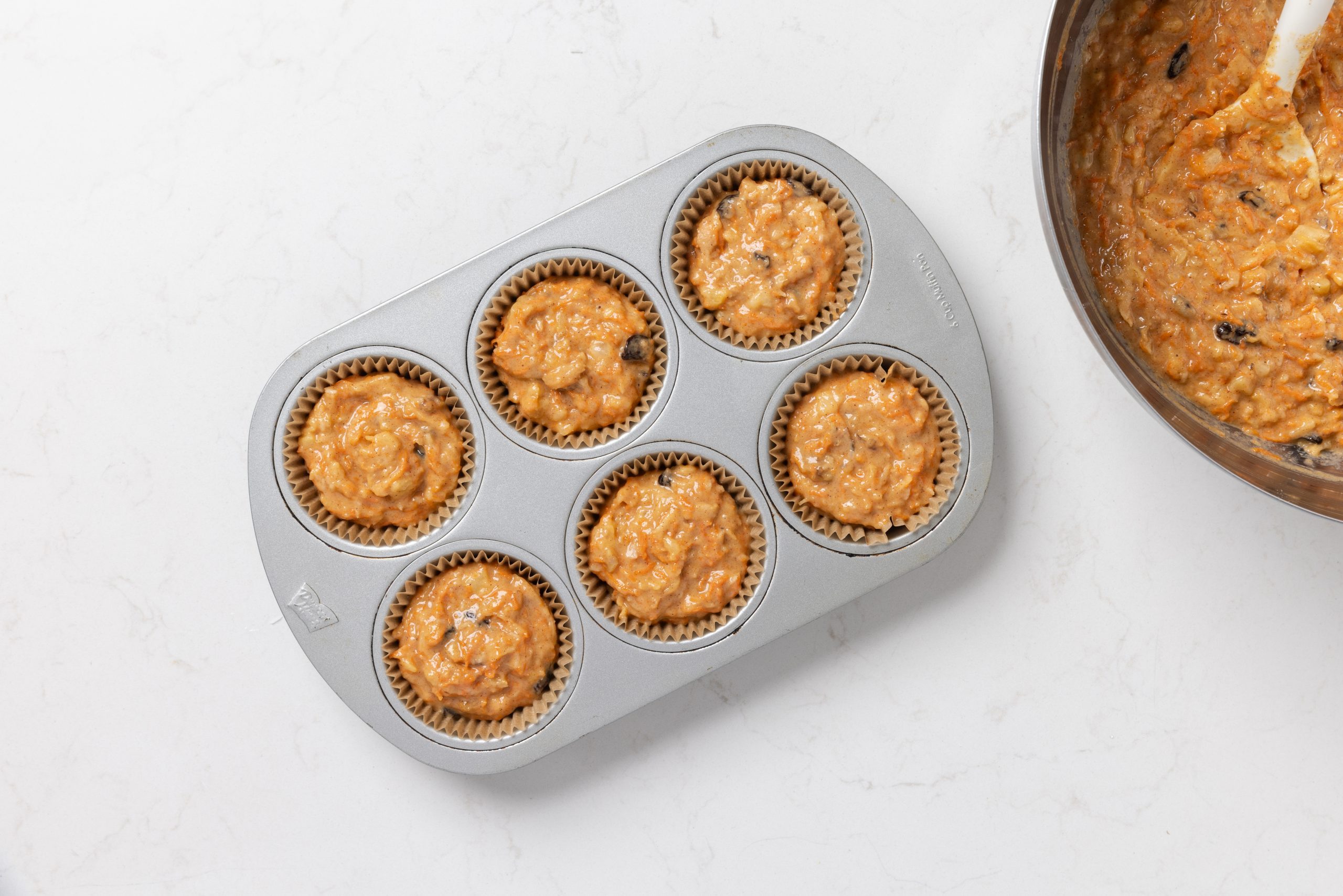 Muffins dough being put into muffin cups.