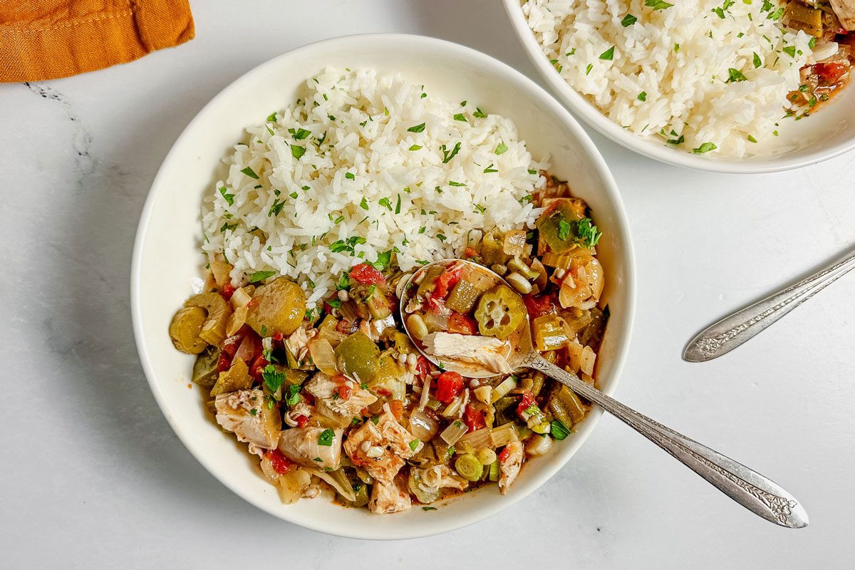 Taste of Home okra gumbo in white ceramic bowls with a linen napkin on a marble surface.